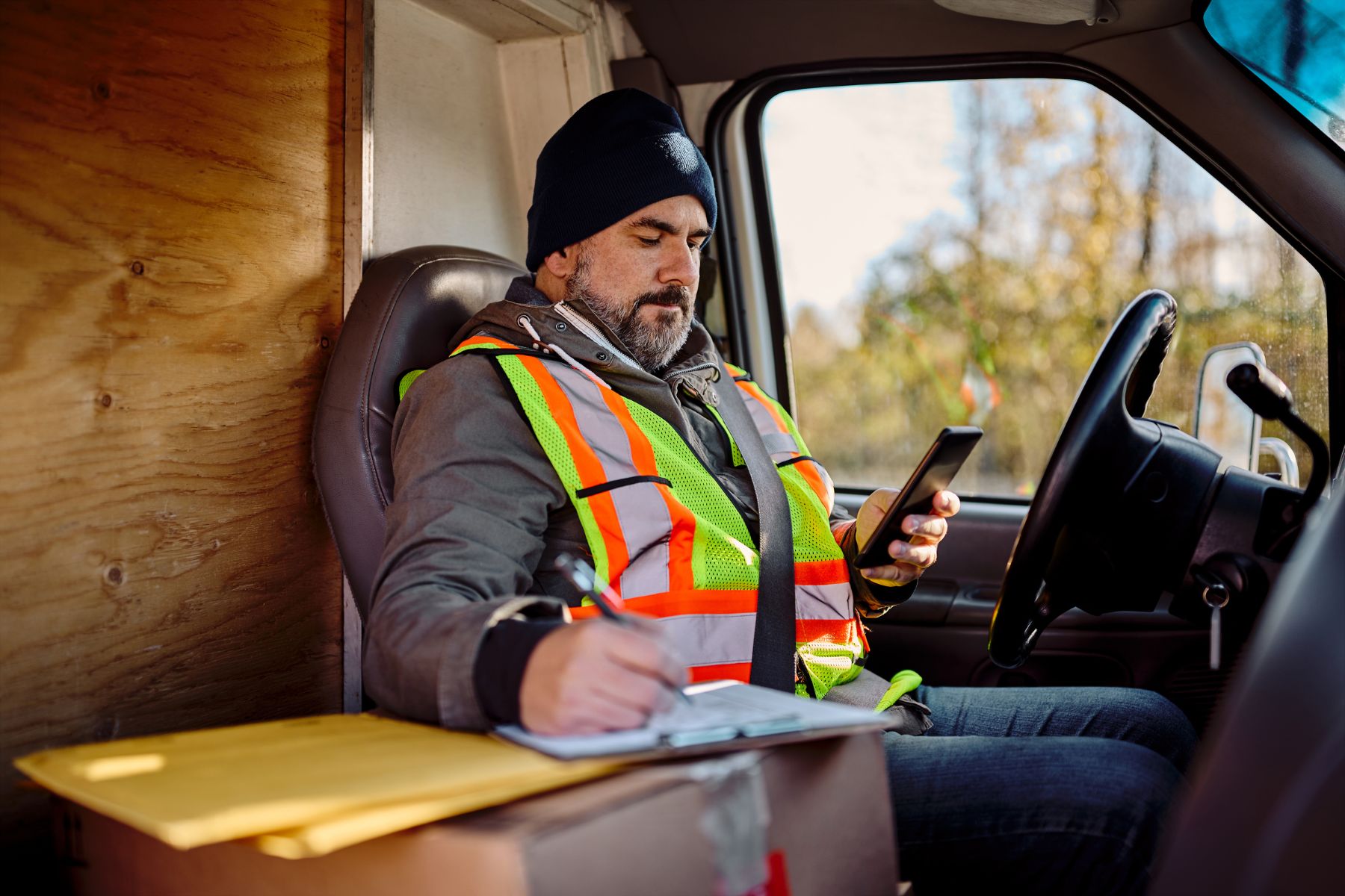 Truck driver using dispatch software on smartphone while recording details on paper for efficient load management and communication
