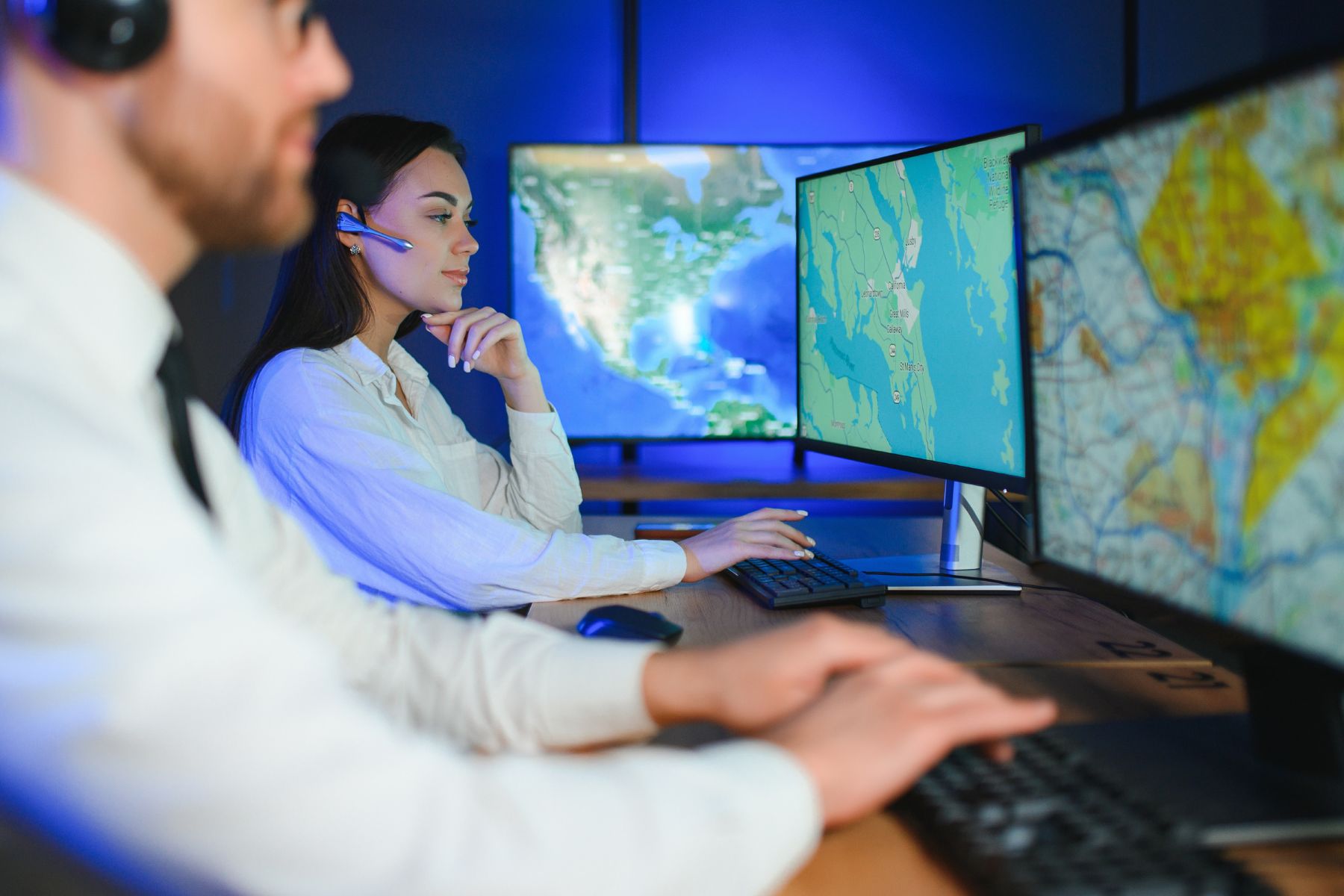 Two logistics professionals collaborating while using truck dispatch software on computer systems for real-time fleet management and route planning
